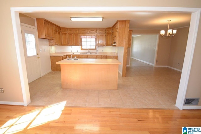 kitchen featuring sink, light hardwood / wood-style flooring, an inviting chandelier, and hanging light fixtures