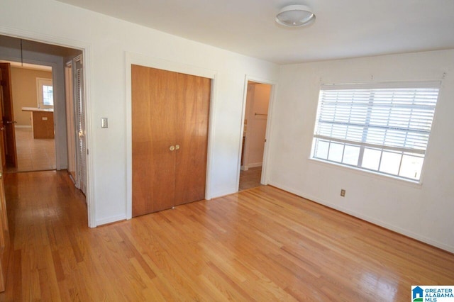 unfurnished bedroom with baseboards, a closet, and light wood finished floors