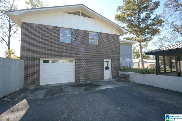 view of side of property with brick siding, a garage, and board and batten siding