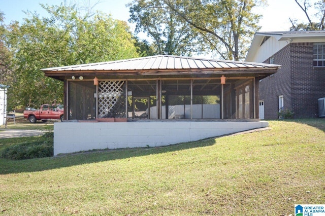 exterior space with a yard, central AC unit, a sunroom, and metal roof