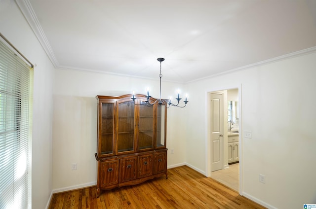 unfurnished dining area featuring crown molding, a healthy amount of sunlight, a notable chandelier, and light wood-type flooring