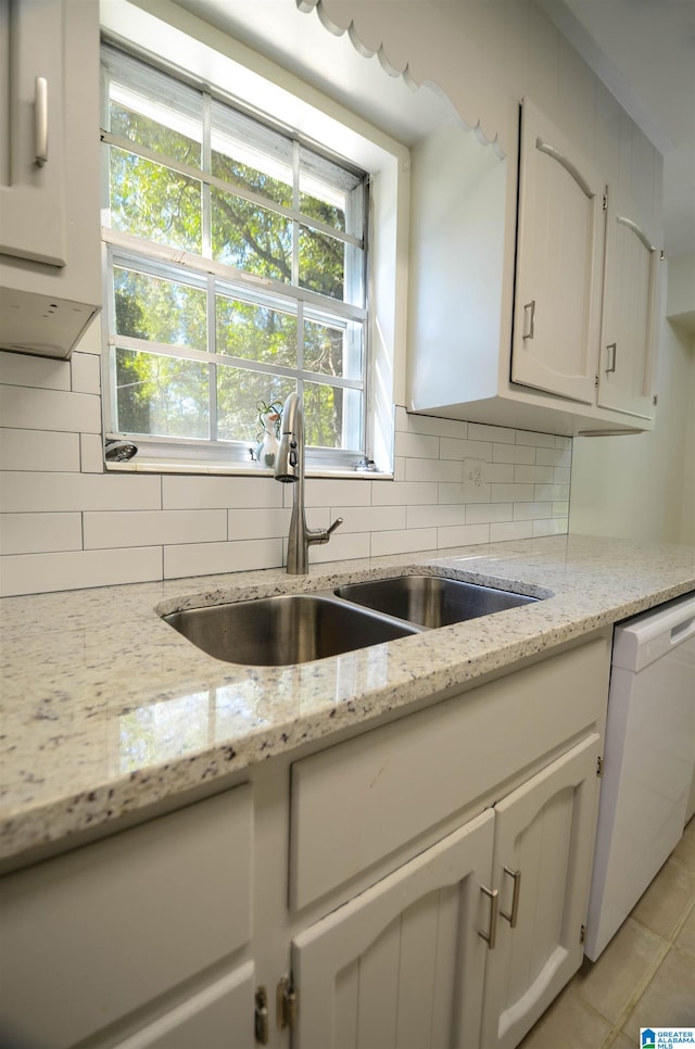 kitchen featuring dishwasher, sink, light stone countertops, and backsplash