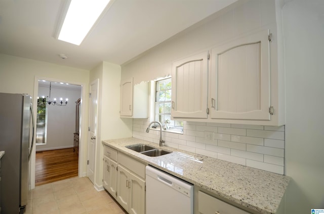 kitchen featuring sink, stainless steel refrigerator, white dishwasher, white cabinets, and backsplash