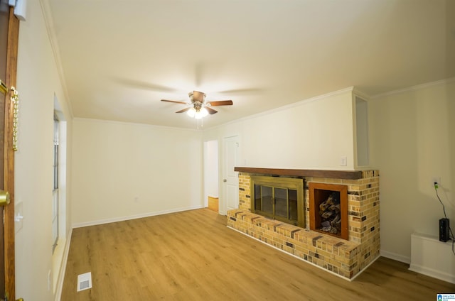 unfurnished living room with ornamental molding, a brick fireplace, and light wood-type flooring