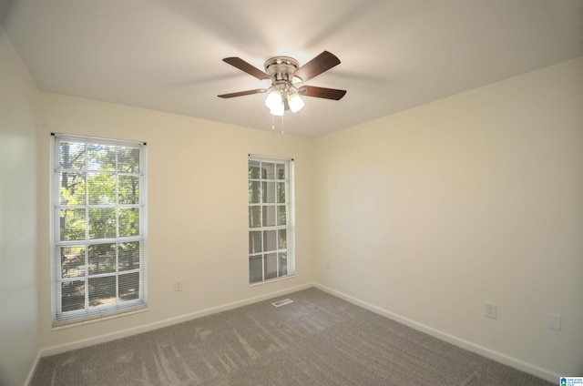 spare room with ceiling fan and dark colored carpet