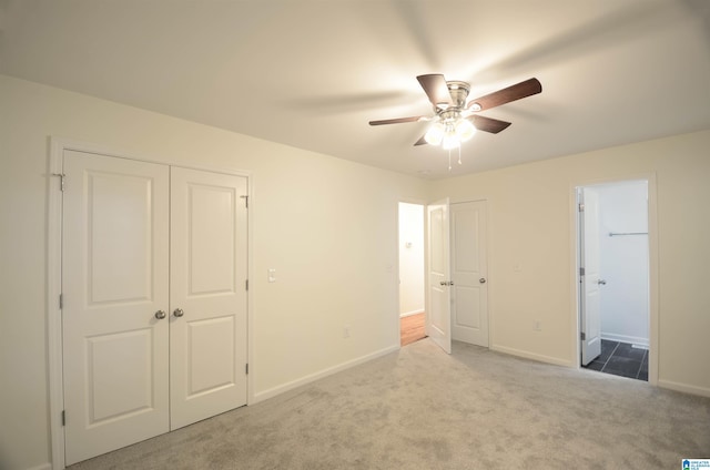 unfurnished bedroom with ensuite bathroom, light colored carpet, and ceiling fan