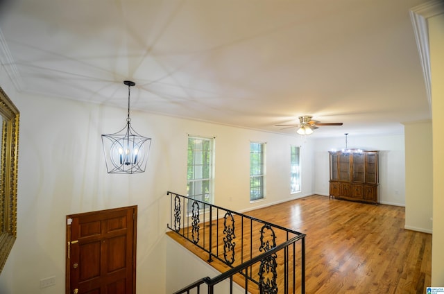 interior space with wood-type flooring, ceiling fan with notable chandelier, and crown molding