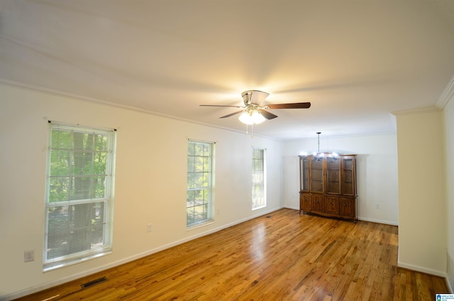 unfurnished room with ceiling fan with notable chandelier, light hardwood / wood-style flooring, and ornamental molding