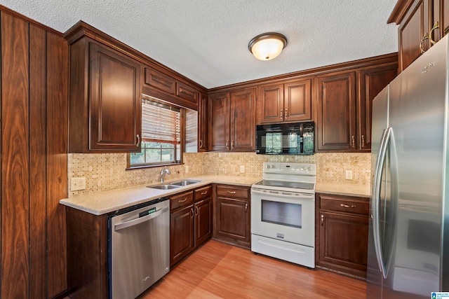 kitchen featuring decorative backsplash, sink, light stone countertops, light wood-type flooring, and appliances with stainless steel finishes