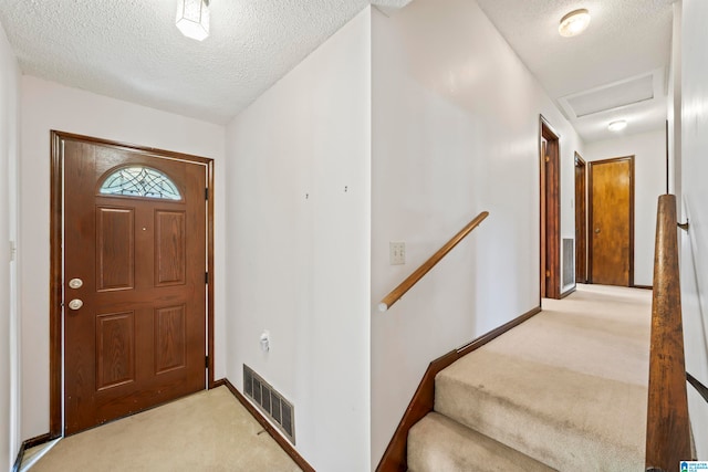 foyer entrance with light carpet and a textured ceiling