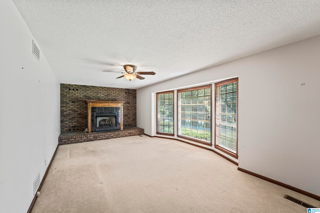 unfurnished living room featuring a brick fireplace, a textured ceiling, carpet, and ceiling fan