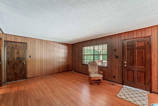 foyer entrance with light hardwood / wood-style floors and wood walls