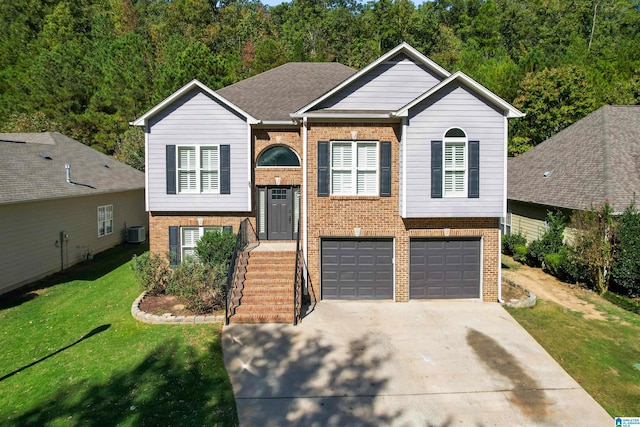 raised ranch featuring a front lawn, central AC unit, and a garage