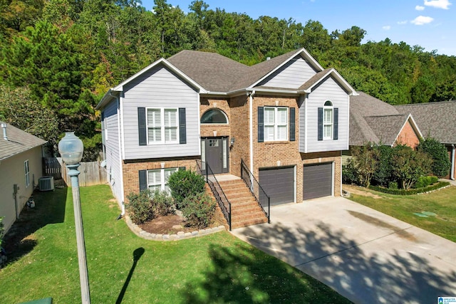 raised ranch featuring cooling unit, a front lawn, and a garage