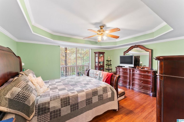 bedroom featuring crown molding, hardwood / wood-style floors, ceiling fan, and a raised ceiling