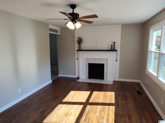 unfurnished living room featuring dark wood-type flooring and ceiling fan