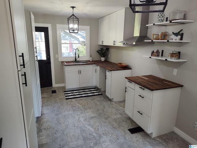 kitchen featuring sink, wood counters, pendant lighting, white cabinets, and a notable chandelier