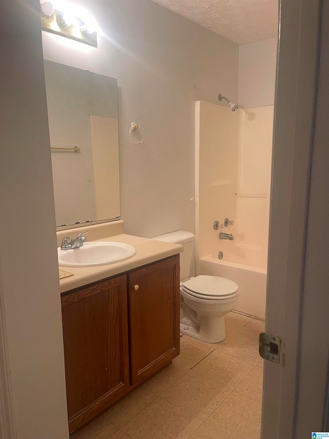 full bathroom with tile patterned floors, toilet, vanity, washtub / shower combination, and a textured ceiling