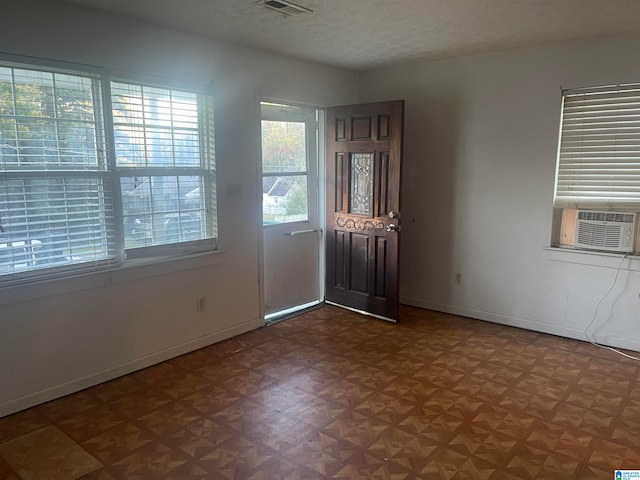 foyer entrance featuring cooling unit, a textured ceiling, and parquet floors