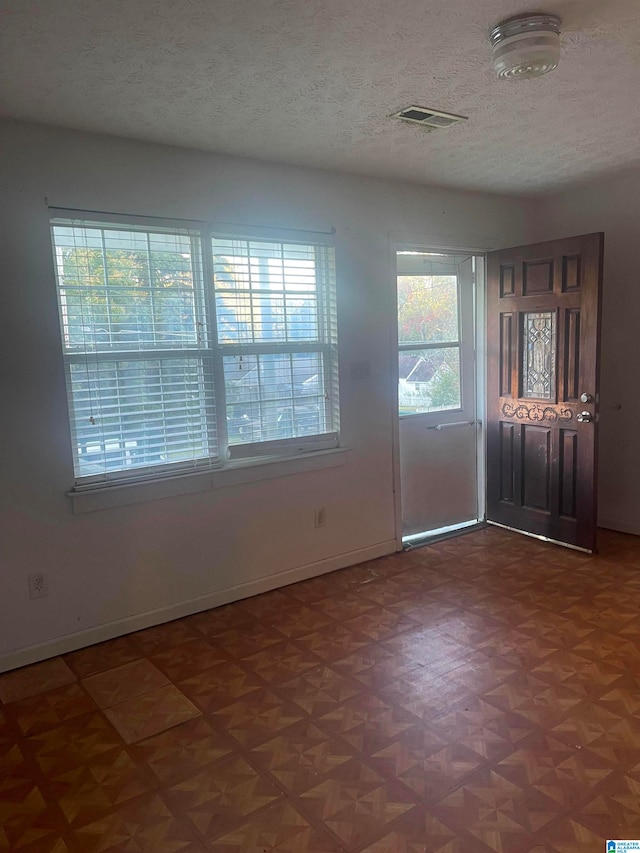 entryway with a textured ceiling and parquet floors