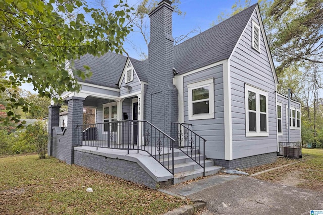 view of front facade featuring covered porch, a shingled roof, a chimney, and crawl space