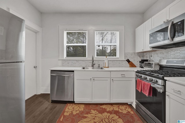 kitchen with decorative backsplash, a sink, white cabinets, light wood finished floors, and stainless steel appliances