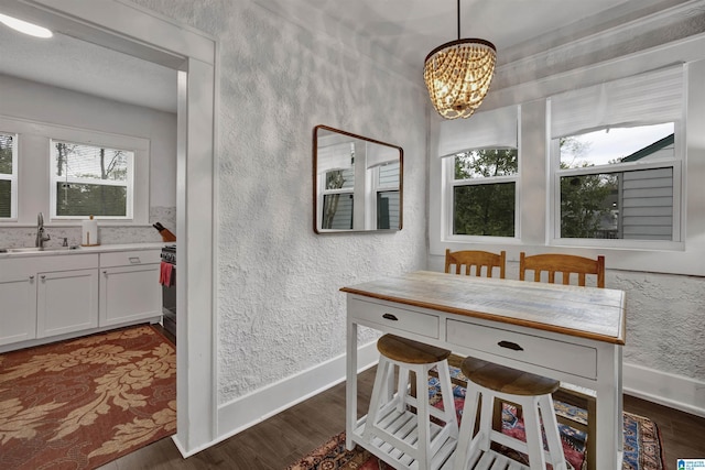 dining area with a textured wall, baseboards, a chandelier, and dark wood-style floors