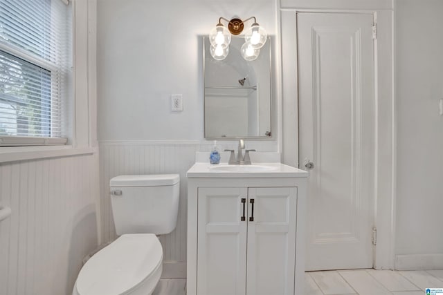 bathroom featuring vanity, tile patterned flooring, wainscoting, and toilet