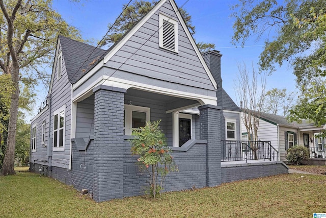 view of property exterior with roof with shingles, a chimney, brick siding, crawl space, and a yard