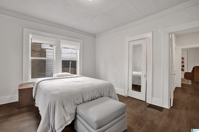 bedroom featuring baseboards, visible vents, and dark wood finished floors