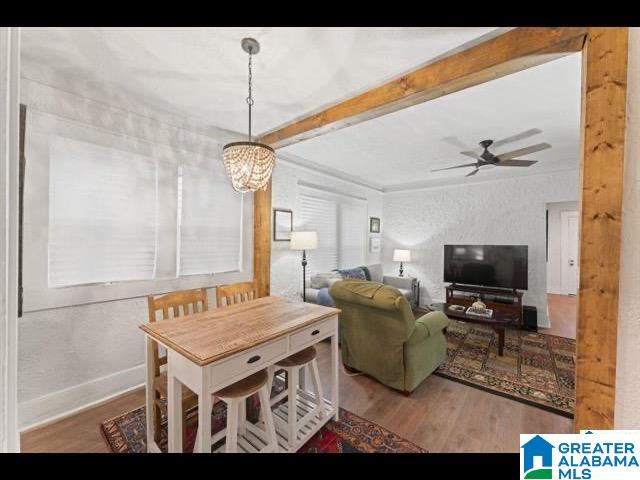 living room with hardwood / wood-style flooring, beamed ceiling, and ceiling fan with notable chandelier