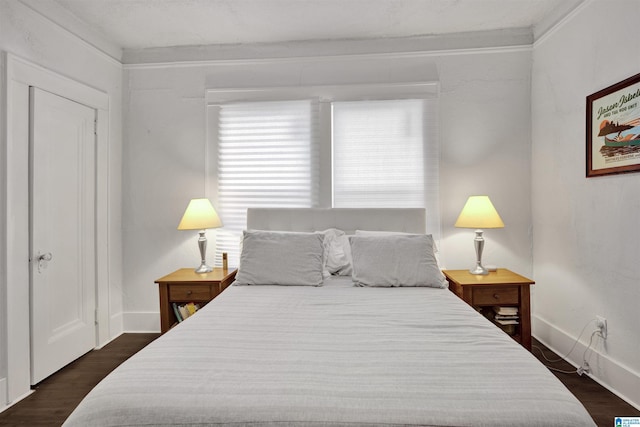 bedroom with baseboards and dark wood-type flooring