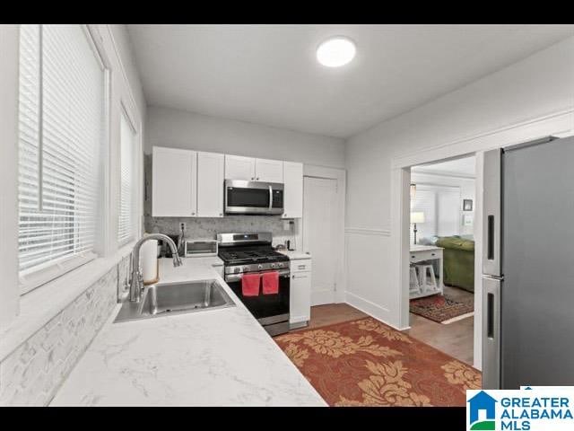 kitchen with sink, white cabinets, stainless steel appliances, and tasteful backsplash