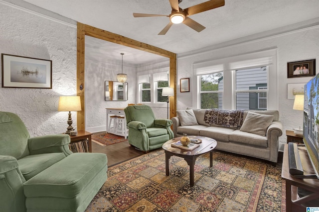 living room featuring baseboards, a textured wall, ceiling fan, and wood finished floors