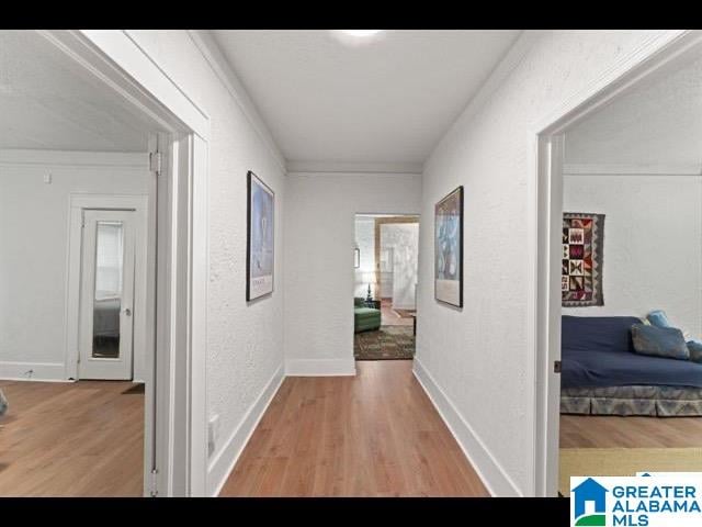 corridor with crown molding and light hardwood / wood-style flooring