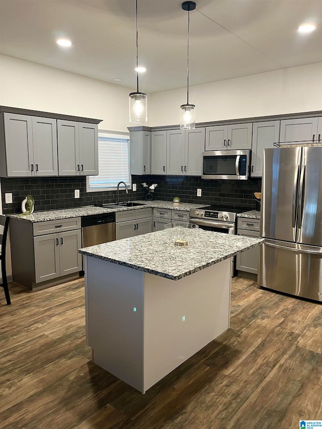 kitchen with sink, a center island, stainless steel appliances, pendant lighting, and dark wood-type flooring