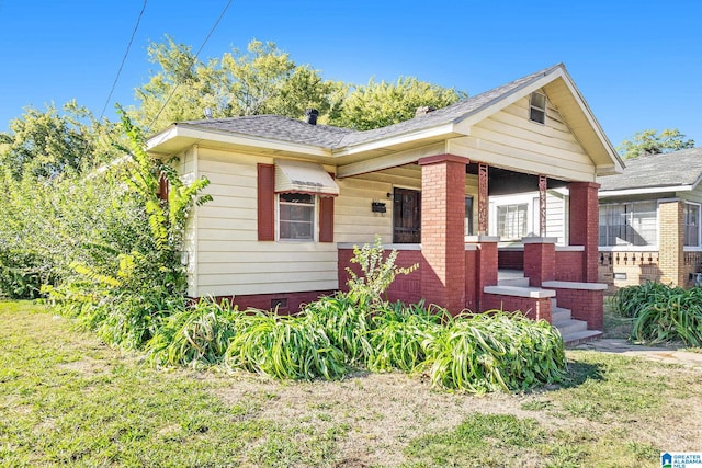 bungalow-style home featuring covered porch and a front lawn