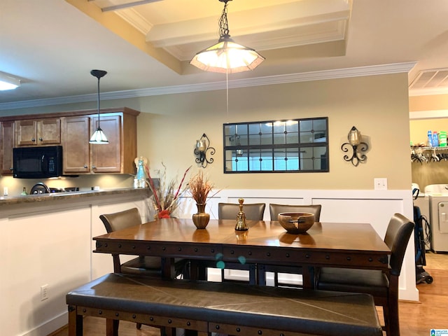 dining space featuring light hardwood / wood-style floors, crown molding, washer / dryer, and a tray ceiling