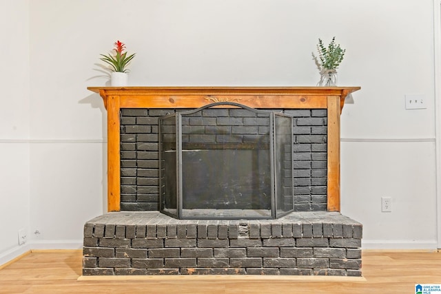 room details featuring a brick fireplace and wood-type flooring