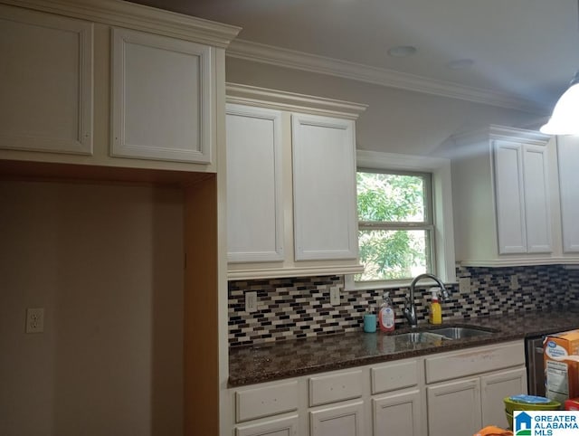 kitchen with sink, dark stone counters, white cabinets, crown molding, and decorative backsplash