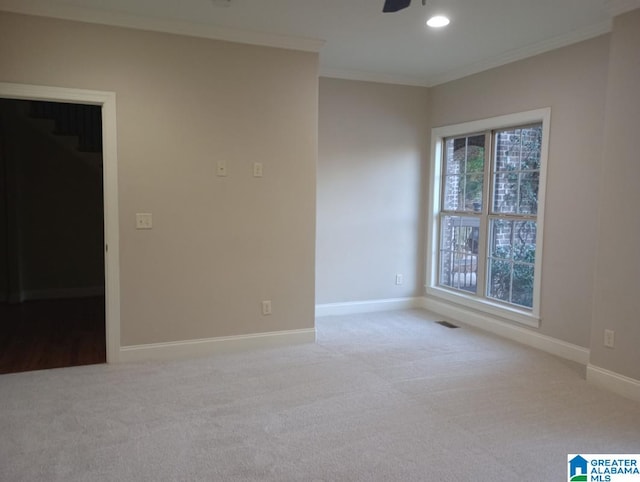 spare room featuring light carpet, ornamental molding, and ceiling fan