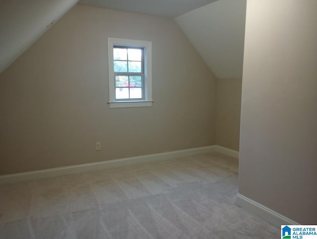 additional living space featuring vaulted ceiling and light colored carpet