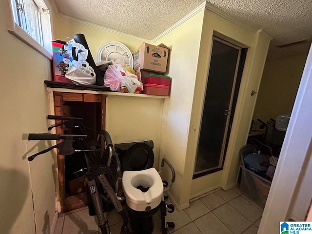 clothes washing area with crown molding, light tile patterned flooring, and a textured ceiling