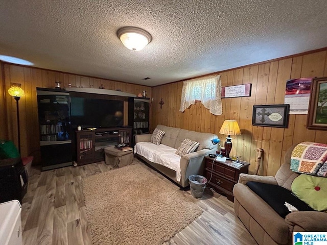 living room featuring wooden walls, a textured ceiling, and light hardwood / wood-style floors