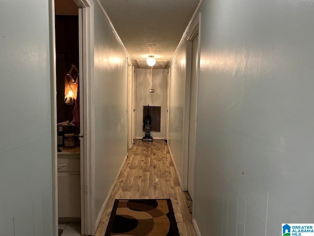 hallway featuring ornamental molding, light hardwood / wood-style flooring, and a textured ceiling