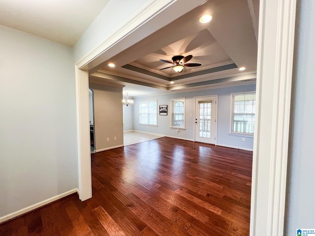 unfurnished room with ornamental molding, ceiling fan with notable chandelier, dark wood-type flooring, and a tray ceiling