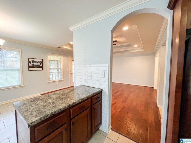 interior space featuring a raised ceiling, crown molding, and light hardwood / wood-style flooring