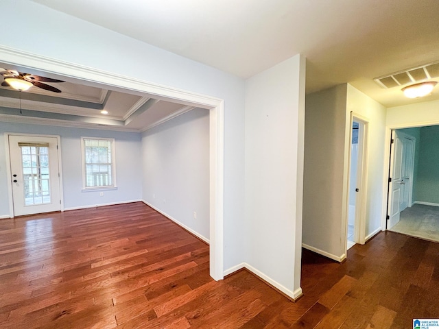 empty room featuring ceiling fan, a raised ceiling, dark hardwood / wood-style floors, and crown molding