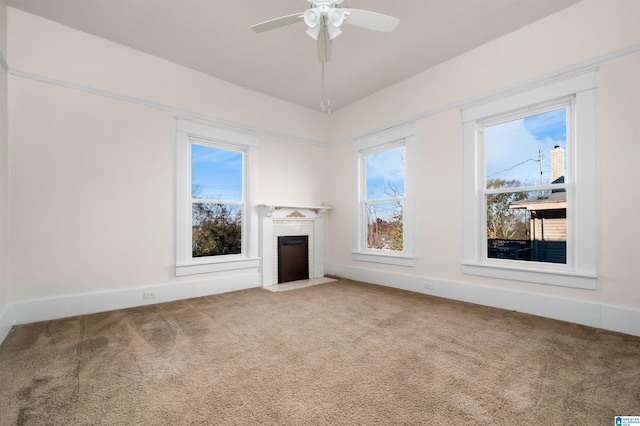 unfurnished living room with carpet, ceiling fan, a fireplace, and plenty of natural light