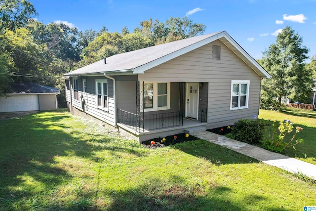 view of front facade with a garage, a front lawn, an outbuilding, and a porch